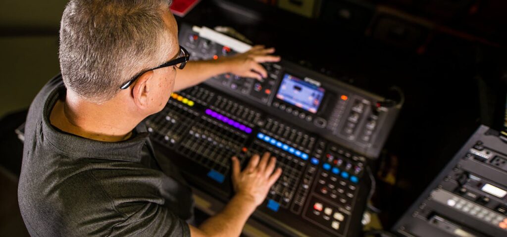 Sound engineer working on a professional audio console in a studio setting, focusing on the mix.